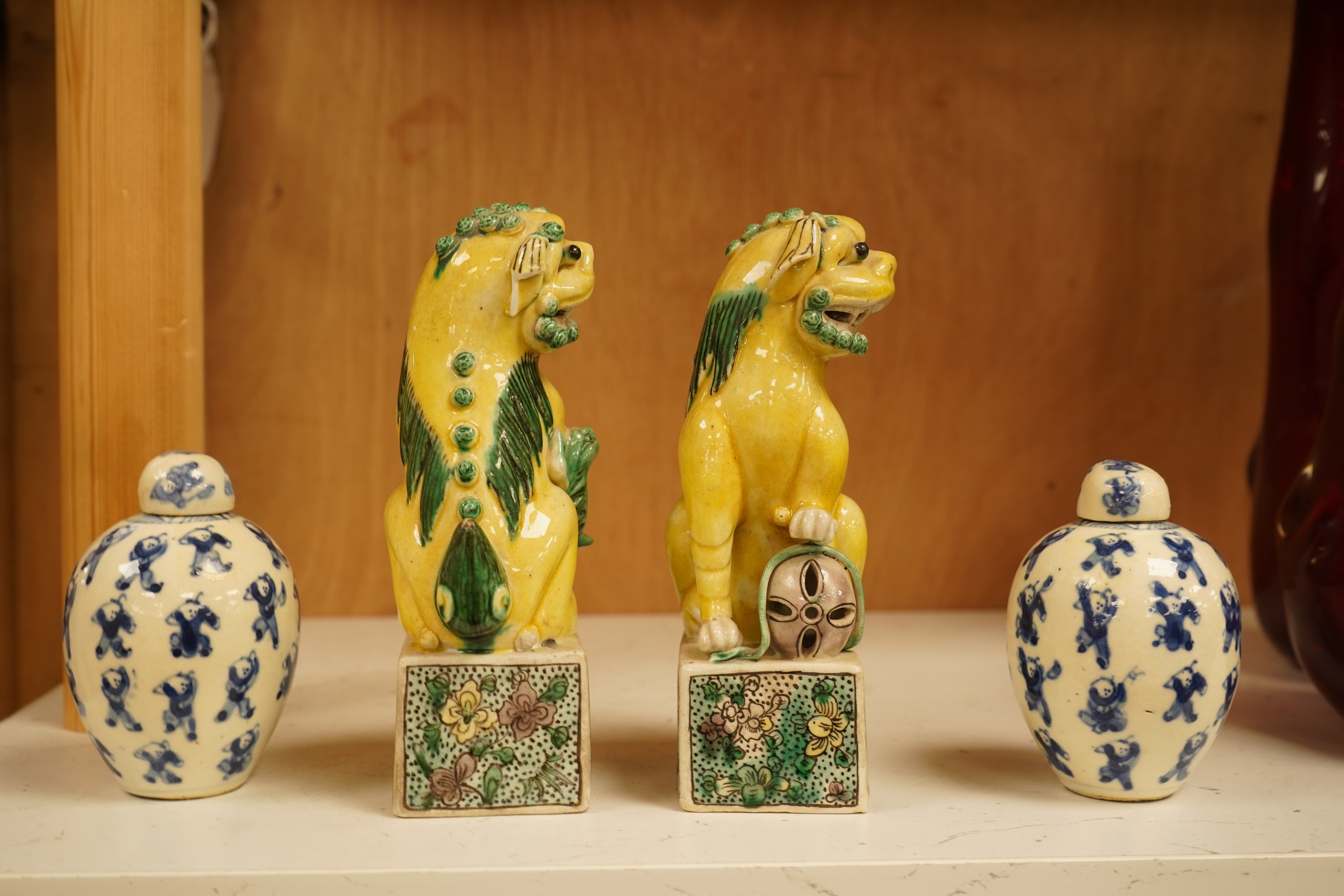 A pair of late 19th/early 20th century Chinese famille verte lion dogs and a similar pair of blue and white miniature ‘boys’ jars and covers, 15cm